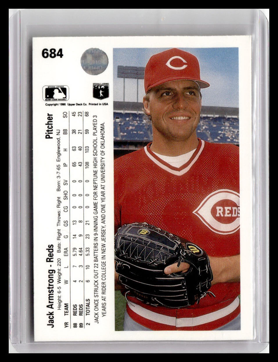 Baseball trading card of a player in a red uniform with 'Reds' logo, held by a card holder.