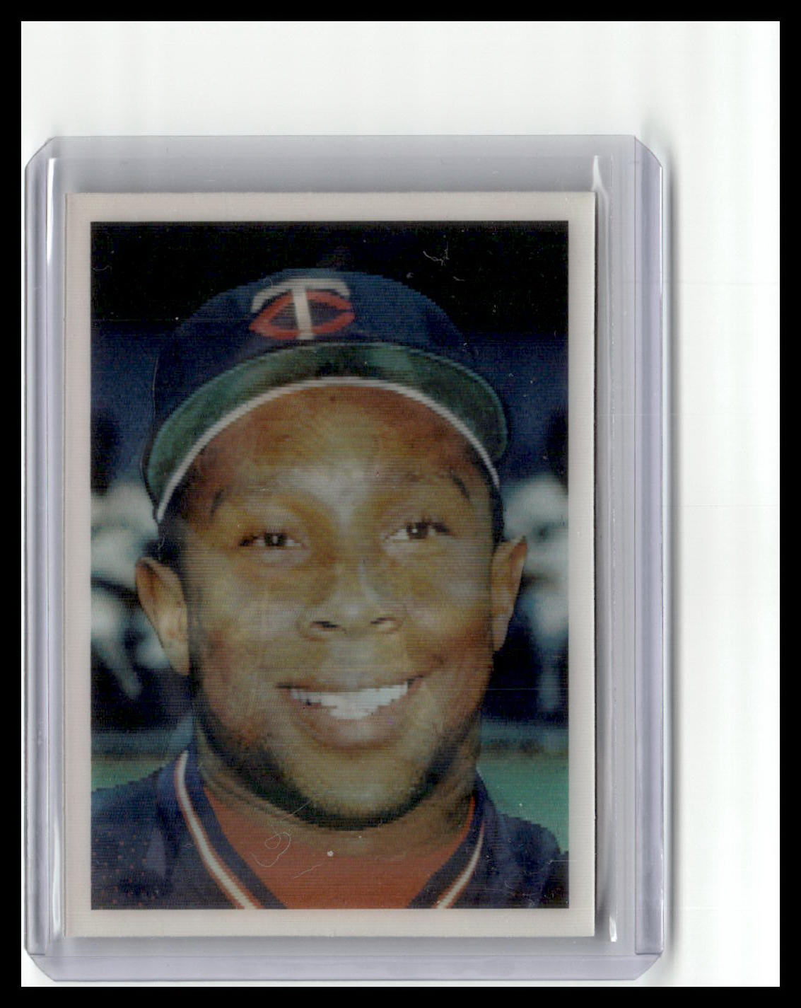 Baseball card of a player wearing a cap with a logo, framed in clear plastic.