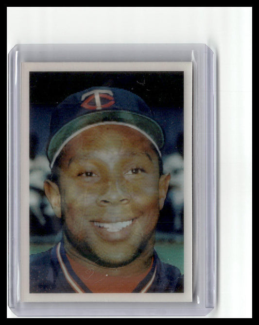 Baseball card of a player wearing a cap with a logo, framed in clear plastic.
